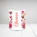 Cow lover ceramic mug with red floral accent. Personalized animal mug on kitchen counter; close-up of sublimated cow design on mug. 
